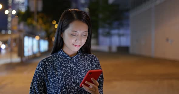 Woman use of cellphone app in city at night