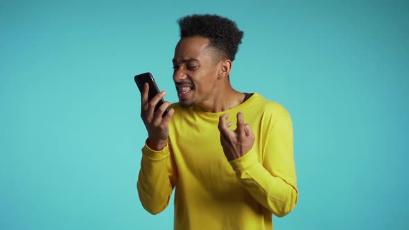 Angry African Man in Yellow Shirt Screaming Down His Mobile Phone in Slow Motion