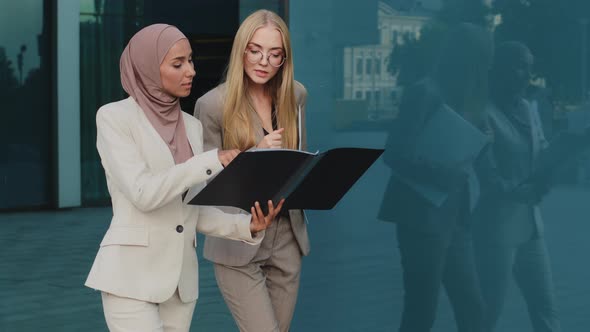 Two Diverse Businesswomen Walking Along Street Holding Folder with Documents Communicate Before