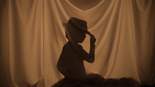 Silhouette of Little Boy Wearing Cowboy Hat and Holding Toy Gun