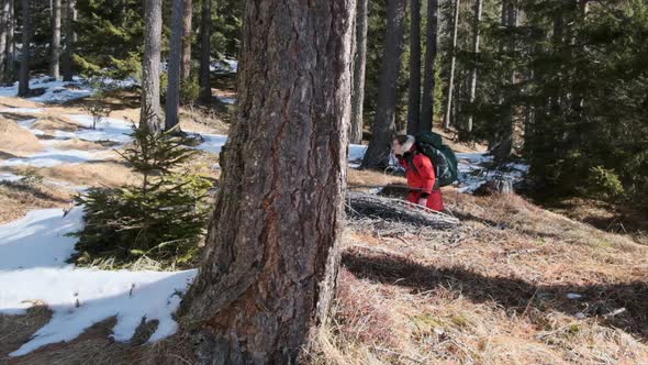 Profile gimbal shot of man walking through snowy forest in slow motion