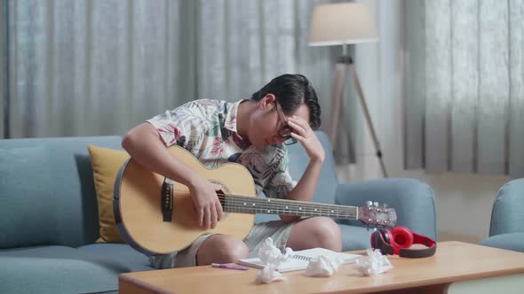 Asian Man Composer With A Guitar Crumpled Paper Then Having A Headache While Composing Music