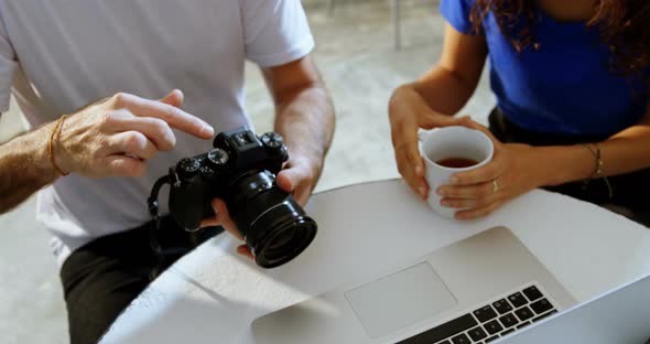 Male photographer and female model discussing over laptop