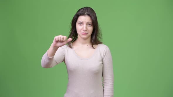 Young Sad Woman Giving Thumbs Down Against Green Background