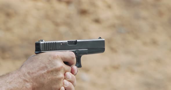 Slow motion of a hand gun firing in a firing range with cartridge flying away