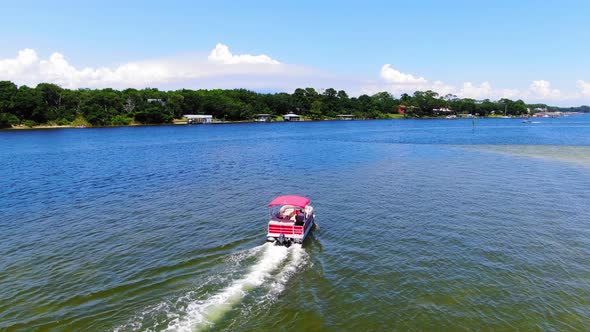 Drone circling a pontoon boat cruising through the sound past some small islands near Destin Florida