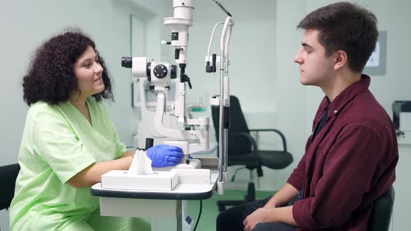 Doctor Talking Using Autorefractor Diagnosing Patient in Hospital Indoors