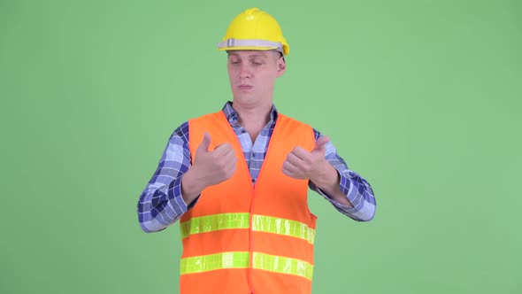 Confused Young Man Construction Worker Choosing Between Thumbs Up and Thumbs Down