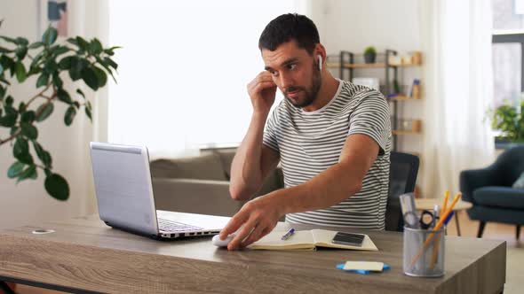 Man with Laptop and Earphones at Home Office