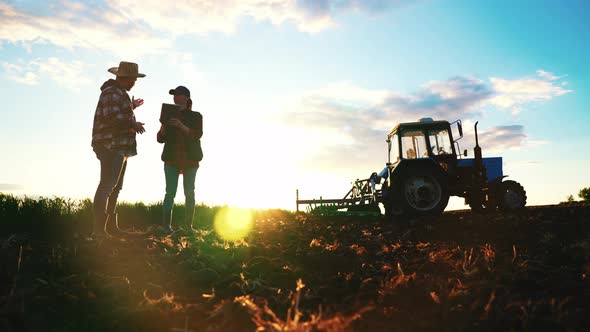 Man Farmer and Female Agronomist on Agricultural Field in Spring Morning Tractor on Farmland Sowing