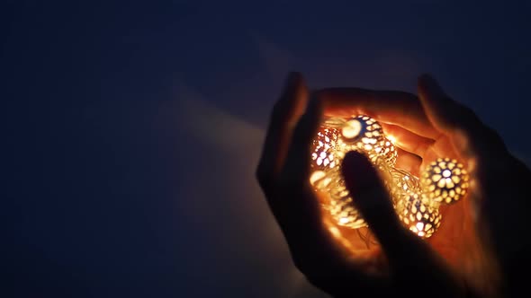 Hands with Light Bulbs in Shape of Heart. Metal Light Bulbs with Delicate Pattern Shine in Dark