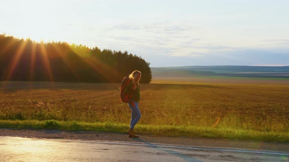 Girl Traveller with Backpack is Walking on Road