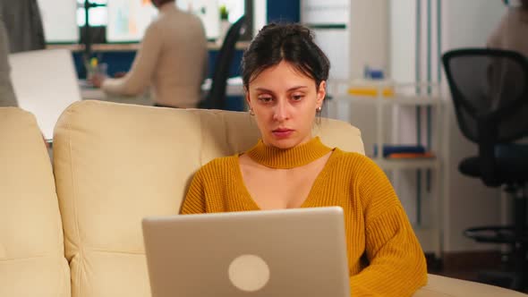 Businesswoman Sitting on Couch Holding Laptop Smiling at Camera