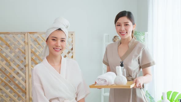 Portrait of Asian young masseuse woman and client looking at camera.