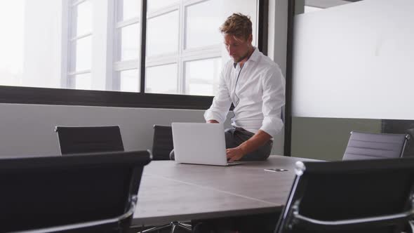 Professional businessman with laptop looking out of a window from his modern office in slow motion