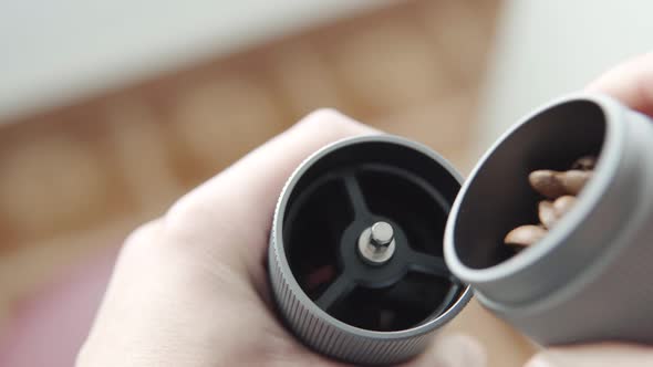 A Man Fills a Coffee Grinder with a Freshly Roasted Premium Coffee Beans