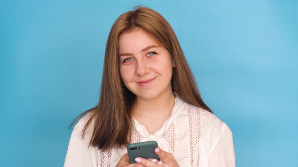 Attractive Brunette young Caucasian woman 20 years old in a white blouse uses the phone, writes a me