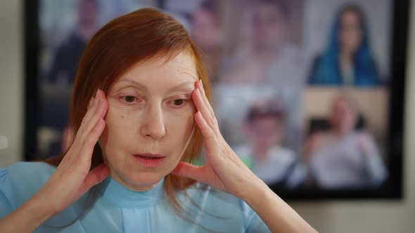 Headshot of Stressed Exhausted Caucasian Woman in Office Rubbing Temples with Blurred Web Conference