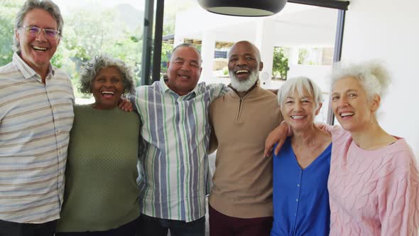 Portrait of happy senior diverse people embracing at retirement home