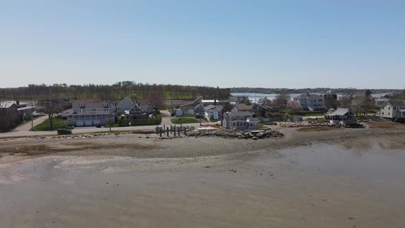 Drone retreat from the shoreline revealing a neighborhood in Hull; a partially built home; and a mud