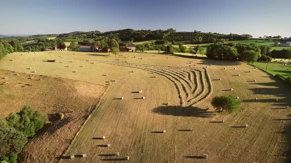 Aerial view of tractor harvesting straw bales in field, Correze, France.