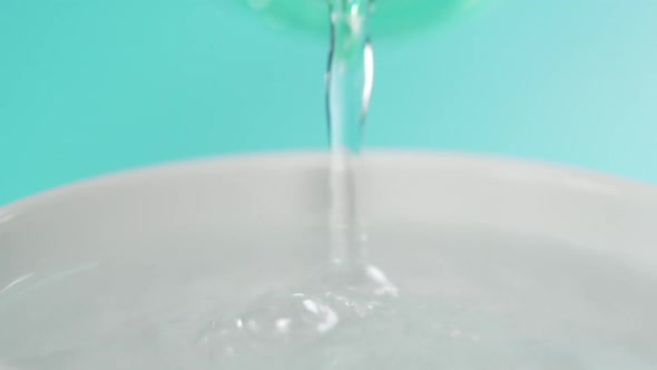 Pure sparkling water flows from a plastic bottle and fills a white cup