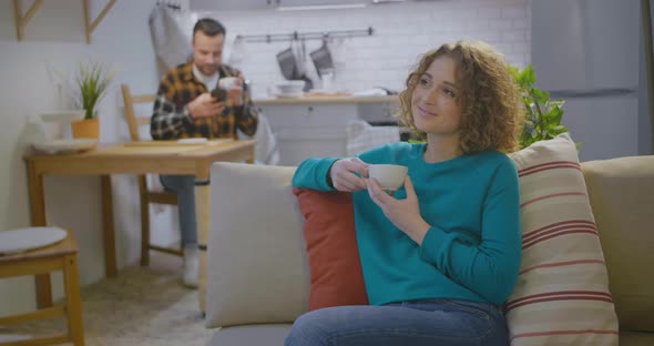 Young Woman Drinking Coffee and Relaxing on Couch at Home