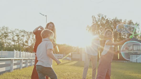 Family Making Soap Bubbles in Summer