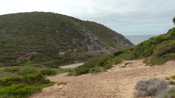 Sandy Beach near Gruta da Adraga Hill on Cloudy Day in Portugal