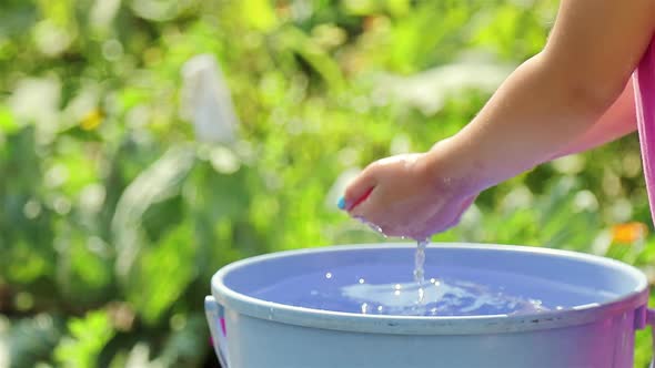 Children's hands are gaining clean water from a bucket on a Sunny summer day. close up.