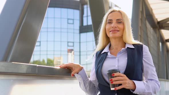 Portrait of Senior Businesswoman Standing Outside a Modern Corporate Building with Coffee Cup