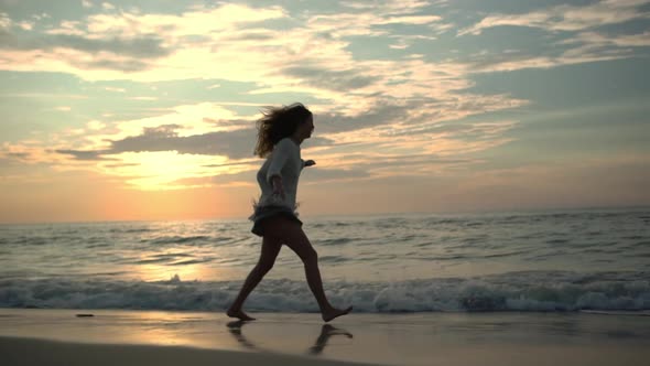 View in Profile Attractive Female Person Running on Wet Sand Leaving Footprints with Stretched Out