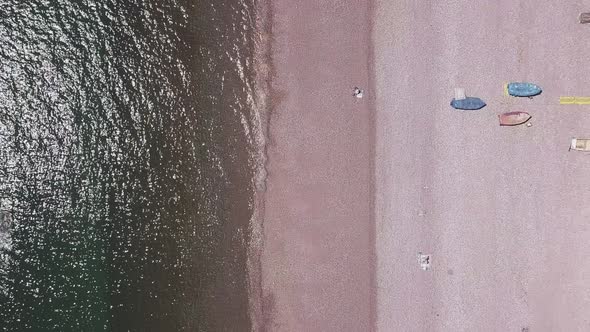 Aerial top shot STATIC CROP, flying forward over a beach and calm ocean