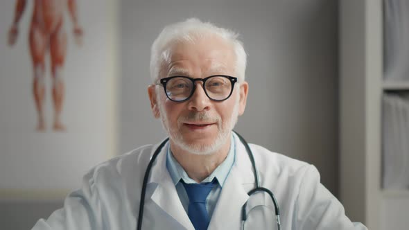 Happy Smiling Mature Doctor Looking at Camera in Office.