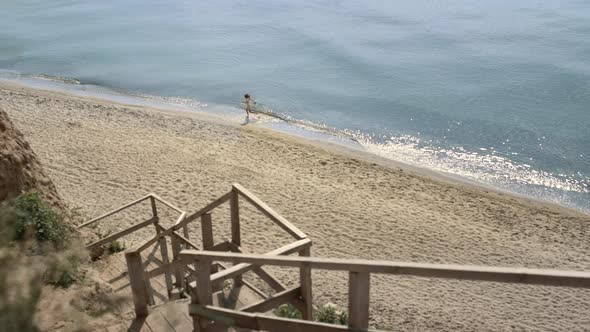 Energetic Woman Running Ocean Waves View in Distance