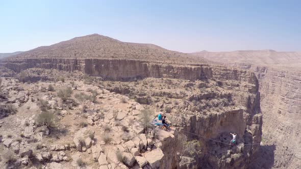 Aerial view of a woman balancing while tightrope walking and slacklining across a canyon