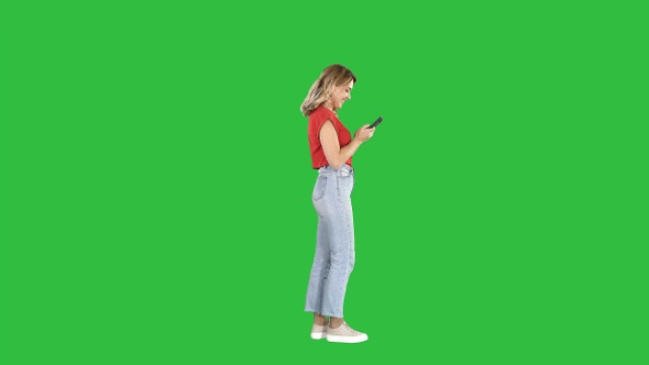 Casual young woman typing on mobile phone on a Green Screen