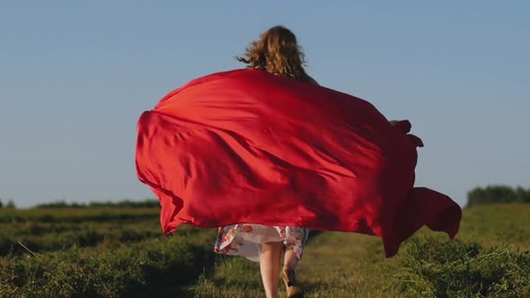 Redhead Woman in White Dress with Red Cloth in Her Hands on Background of Field