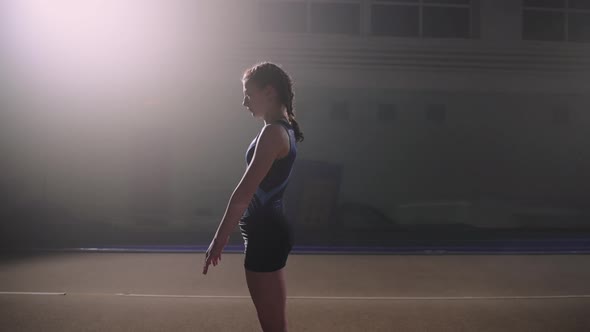 Schoolgirl with Braids is Training Alone in Sports Hall Performing Floor Exercise Two Flip Back