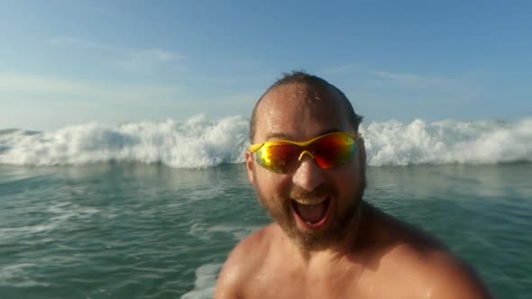 Active man having fun splashing with big sea waves breaking on his head. Slow-motion