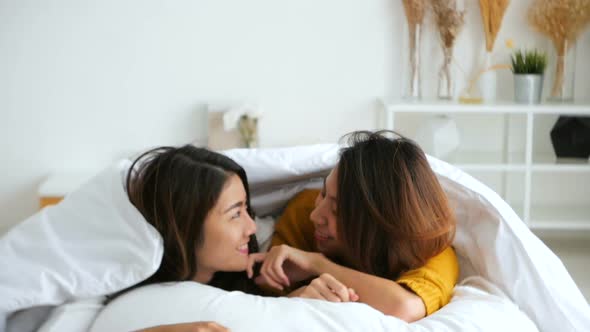 Beautiful young asian women lesbian happy couple hugging and smiling while lying together