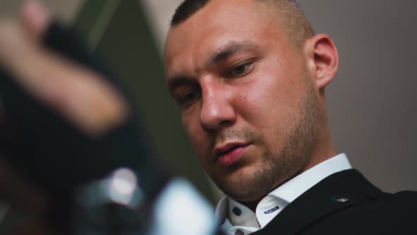 Concentrated Man in Black Suit with Shirt Looks Down in Room