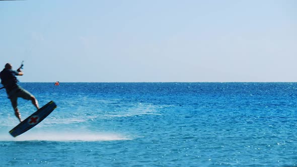 Kite surfer landing a small jump on the beautiful calm blue ocean in Bonaire, Caribbean