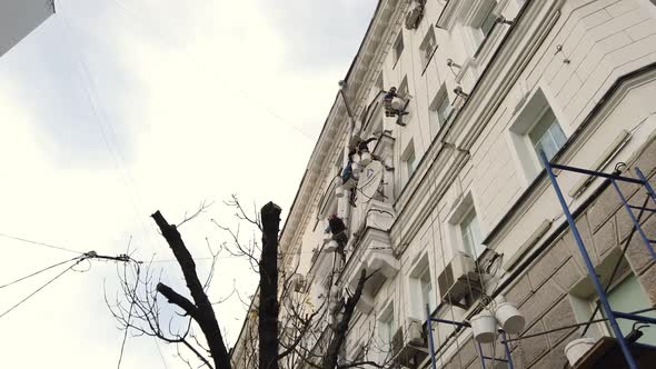 Industrial painters restore the facade of an old high-rise residential building 