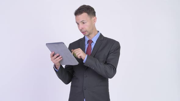 Studio Shot of Businessman Using Digital Tablet and Looking Shocked