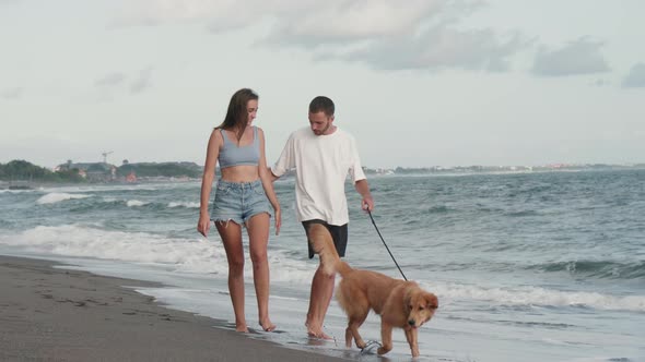 Loving Couple Walking Dog Along Ocean