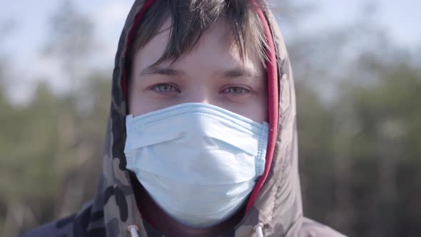 Close-up Face of Young Caucasian Man in Protective Face Mask Outdoors. Portrait of Brunette Boy with
