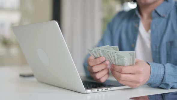 Close Up of Man Counting Dollars While Working on Laptop