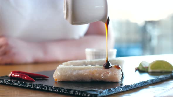 Pouring a Sauce on Serving Original Asian Spring Rolls Closeup