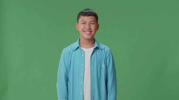 Young Asian Boy Warmly Smiling On Green Screen Background In The Studio